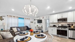 Ein modernes Wohnzimmer mit Sofa, Esstisch und Küchenzeile inklusive Geräte.