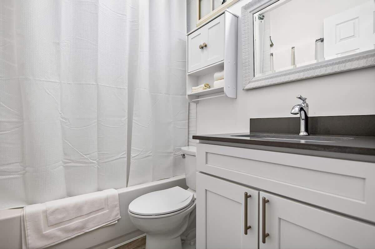 Ein Badezimmer mit Toilette, Badewanne, Waschbecken und Spiegel.