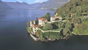 Ein See gelegen Anwesen mit Hauptgebäude, einem Turm und einem gepflegten Garten.