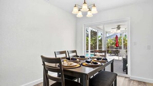 Comedor con una mesa lista para cuatro personas, sillas y una lámpara en el techo.