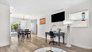 Una sala de estar moderna con comedor, un televisor de pantalla plana, una lámpara y vistas al exterior.