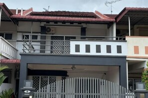 A multi-story residential building with a balcony, a garage, and a gated entrance. - JL Homestay Bahau (Bahau)