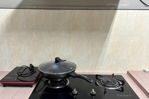 A kitchen with a stove, a pan, and a power strip. - JL Homestay Bahau (Bahau)