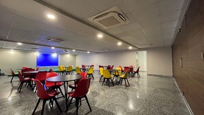 A conference room with tables and chairs, a projector screen, and a blue accent wall. - EXE Banquet and Conference Hall Gurgaon (Gurugram)