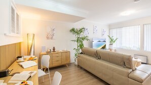 Un salon moderne avec un canapé, une table à manger, des chaises, une plante et des œuvres d’art accrochées aux murs.
