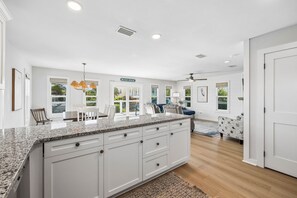A spacious kitchen with a granite countertop, white cabinetry, and a view of the beach. - Private Beach Boardwalk | Pet Friendly (Port St. Joe)