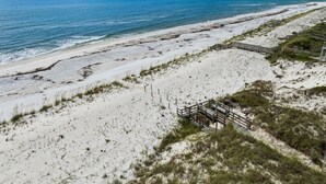 Ein Strand mit einer Holzpromenade, die zu einem sandigen Bereich mit spärlicher Vegetation führt.