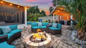 A patio with a fire pit, outdoor seating, and string lights. - Pool and Hot Tub Home with Pickle Ball Court and Walk to Downtown (St. Augustine)