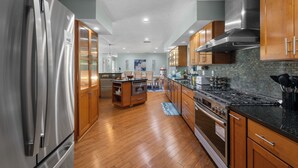 A modern kitchen with stainless steel appliances, wooden cabinets, and a central island. - Pool and Hot Tub Home with Pickle Ball Court and Walk to Downtown (St. Augustine)