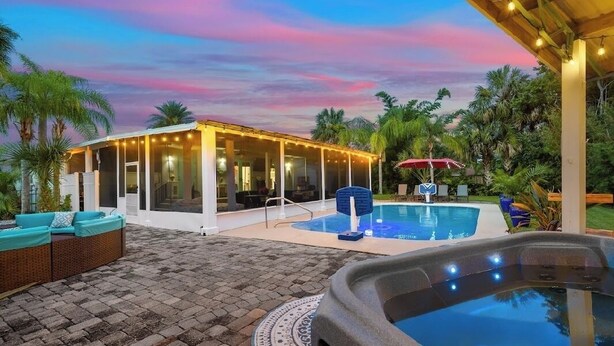 A pool area with a hot tub, lounge chairs, and a covered seating area with string lights. - Pool and Hot Tub Home with Pickle Ball Court and Walk to Downtown (St. Augustine)