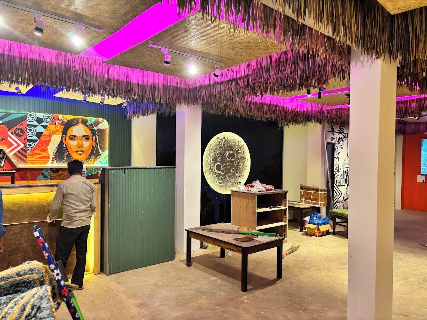 A room with a mural, a wooden table, and a green door.
