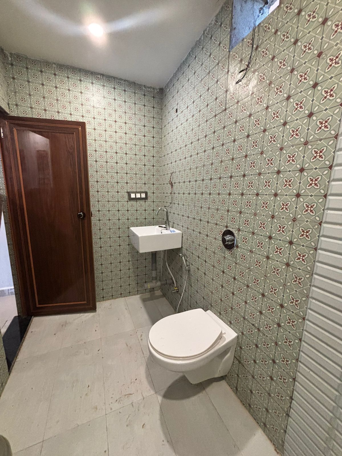 A small bathroom with a toilet, sink, and patterned walls.