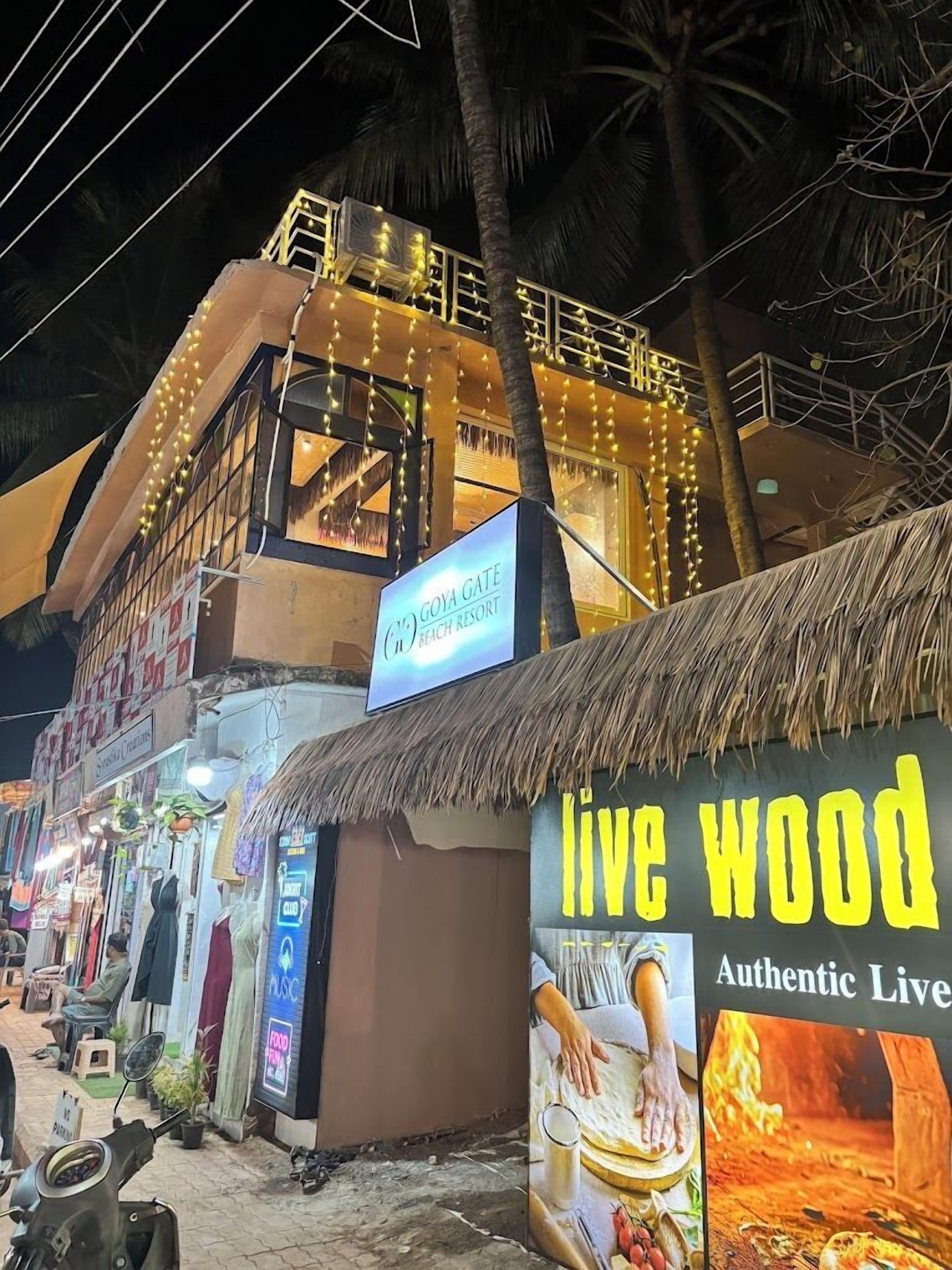 Un edificio con un letrero que dice 'Goya Gate Beach Resort' y un letrero 'Live Wood' que anuncia madera viva auténtica.