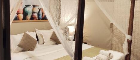 A four-poster bed with a canopy, white linens, and a green throw blanket.