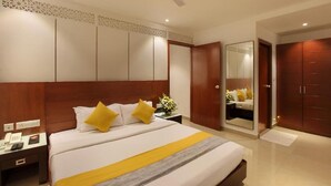 Une chambre d’hôtel équipée d’un lit, d’une table de chevet, d’un miroir, d’une armoire et d’un ventilateur de plafond.