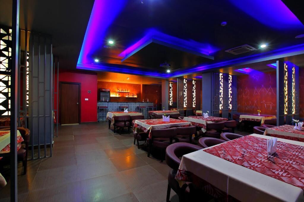 Un restaurante con mesas y sillas, una zona de bar y una pared roja.
