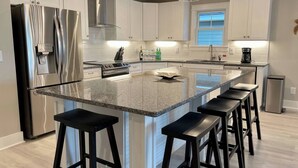 Una cucina moderna con una grande isola, elettrodomestici in acciaio inossidabile e sgabelli da bar.