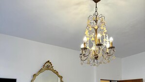 A room with a large mirror, a chandelier, a wooden dresser, and a door leading to another room. - madoneta apartment (Venice)