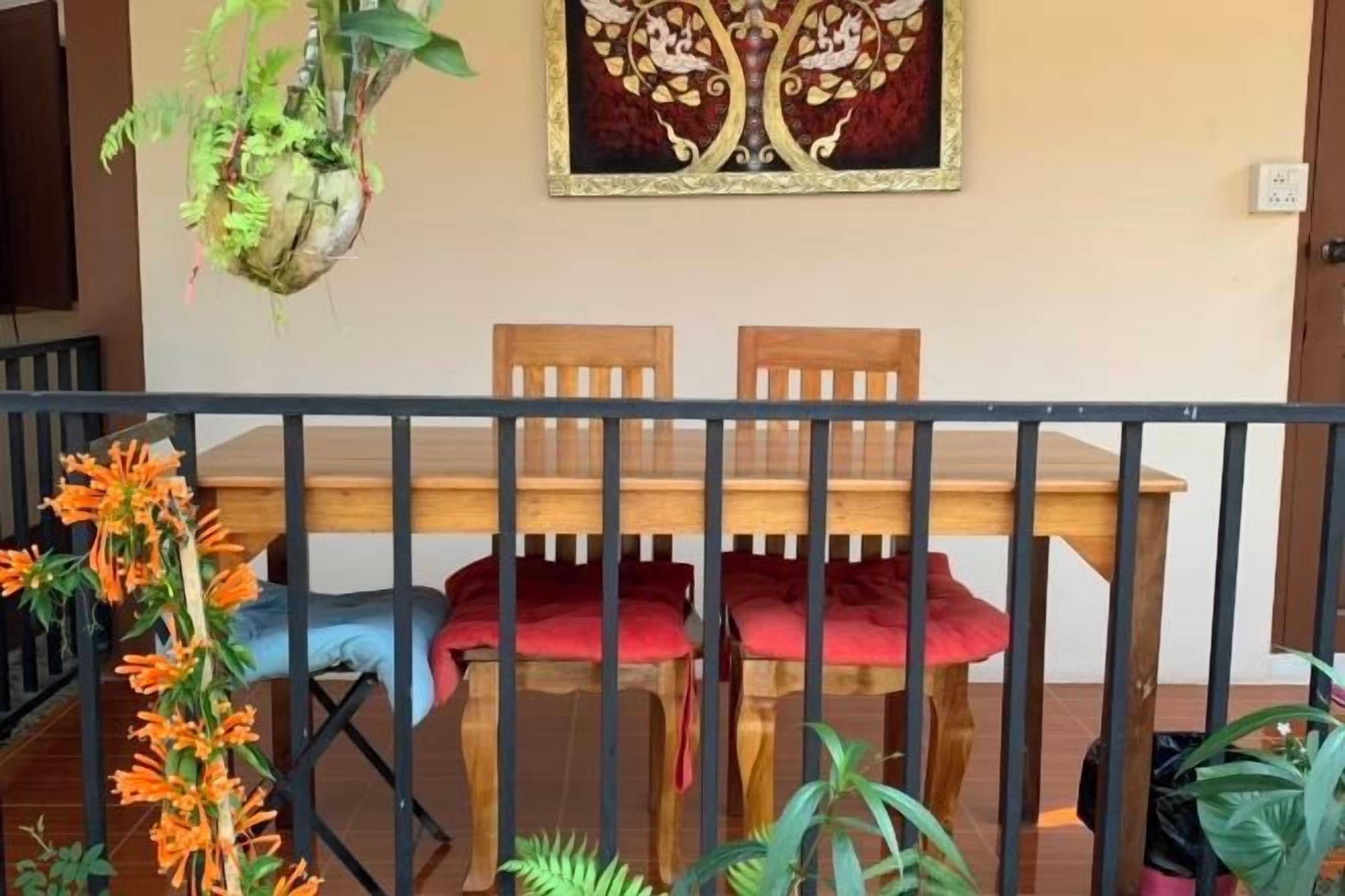 A dining area with a wooden table and chairs, a hanging plant, and a framed artwork on the wall.