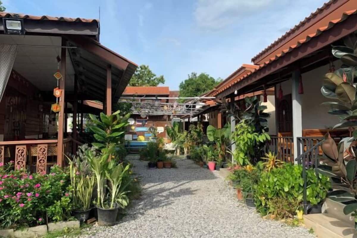 Un patio con plantas en macetas, un sendero de grava y arquitectura tradicional.