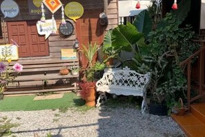 A wooden building with a bench, potted plants, and a white fence.