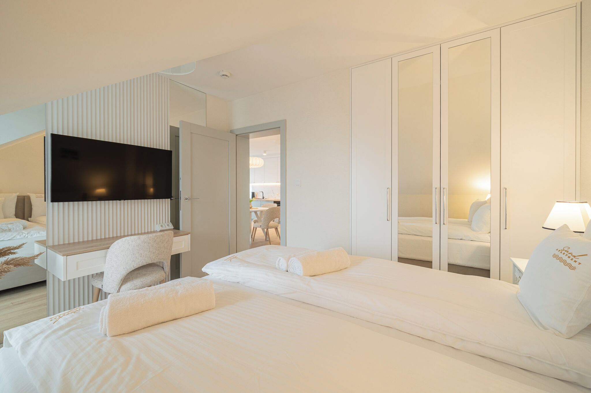 Een hotelkamer met een bed, een bureau met stoel, een televisie, een kledingkast en een badkamer, zichtbaar door een geopende deur.