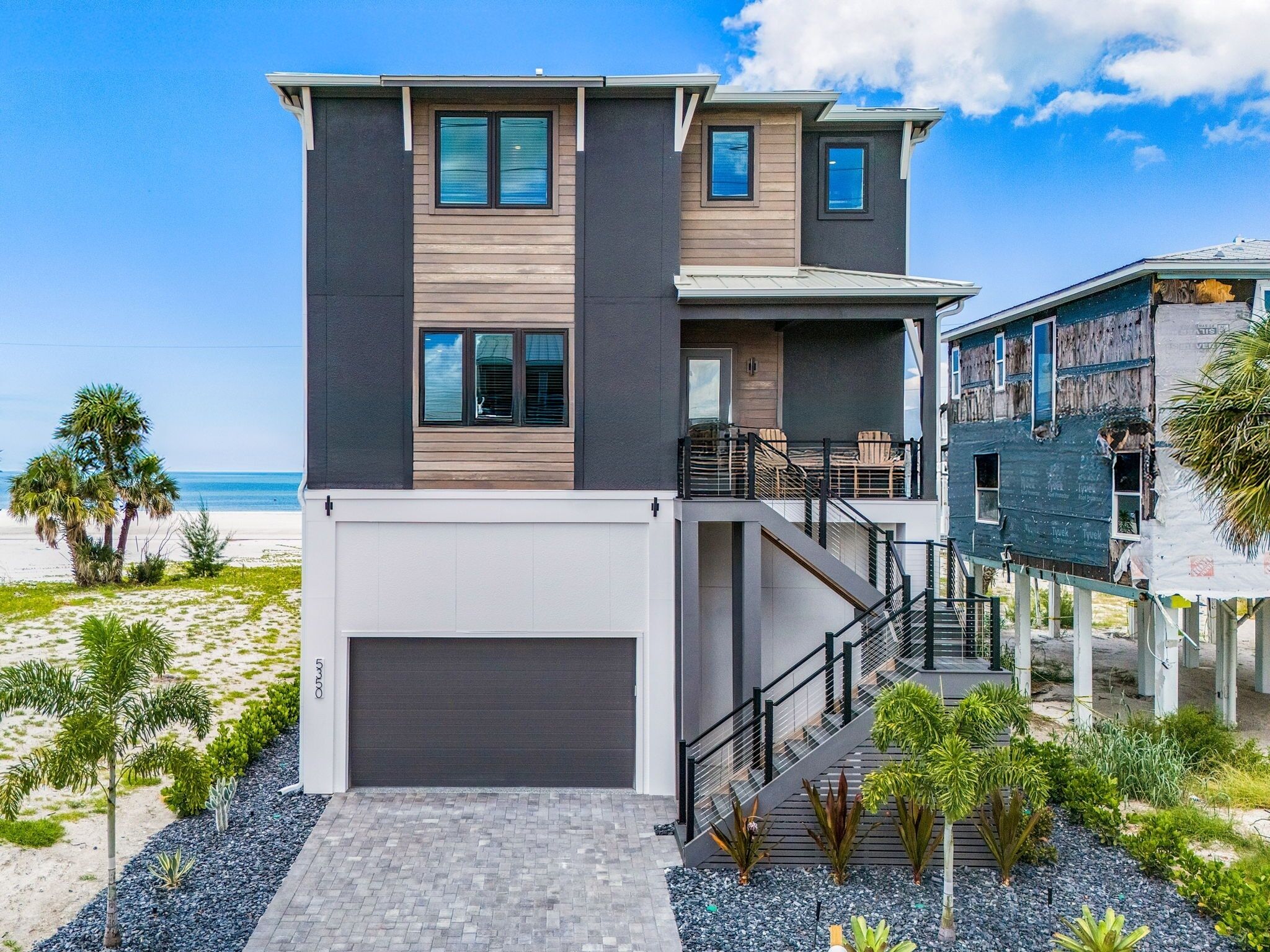 Una moderna casa a due piani con un balcone, un garage e vista sulla spiaggia.