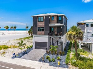 A modern two-story house with a balcony, located near a beach. - 5350 Chasing Sunshine: 5bd/4.5ba Pool Home! 5 Bedroom Home (Fort Myers Beach)