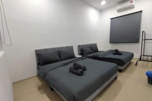 A room with two beds, a projector screen, and a clothes rack.