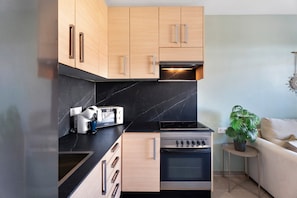 Una cocina moderna con armarios de madera, horno empotrado y encimera con tostadora.