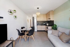 Una cocina moderna con refrigerador, estufa y comedor con sillas y mesa.