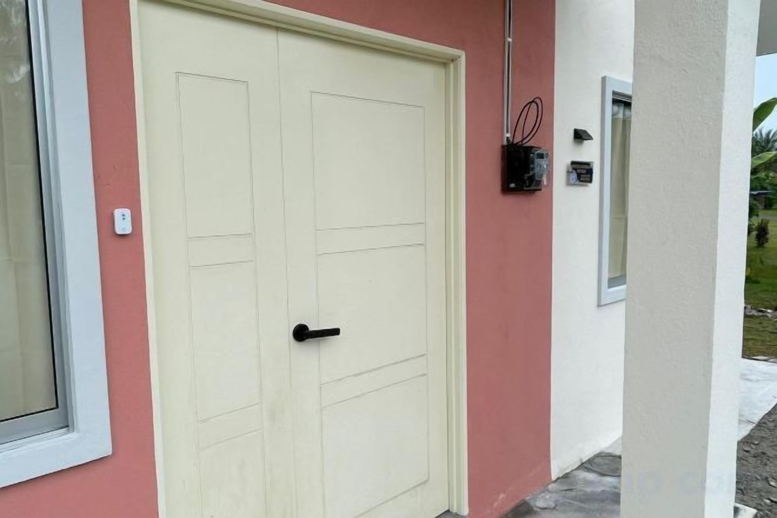 A closed door with a handle, a window with a white frame, and a wall-mounted electrical box.