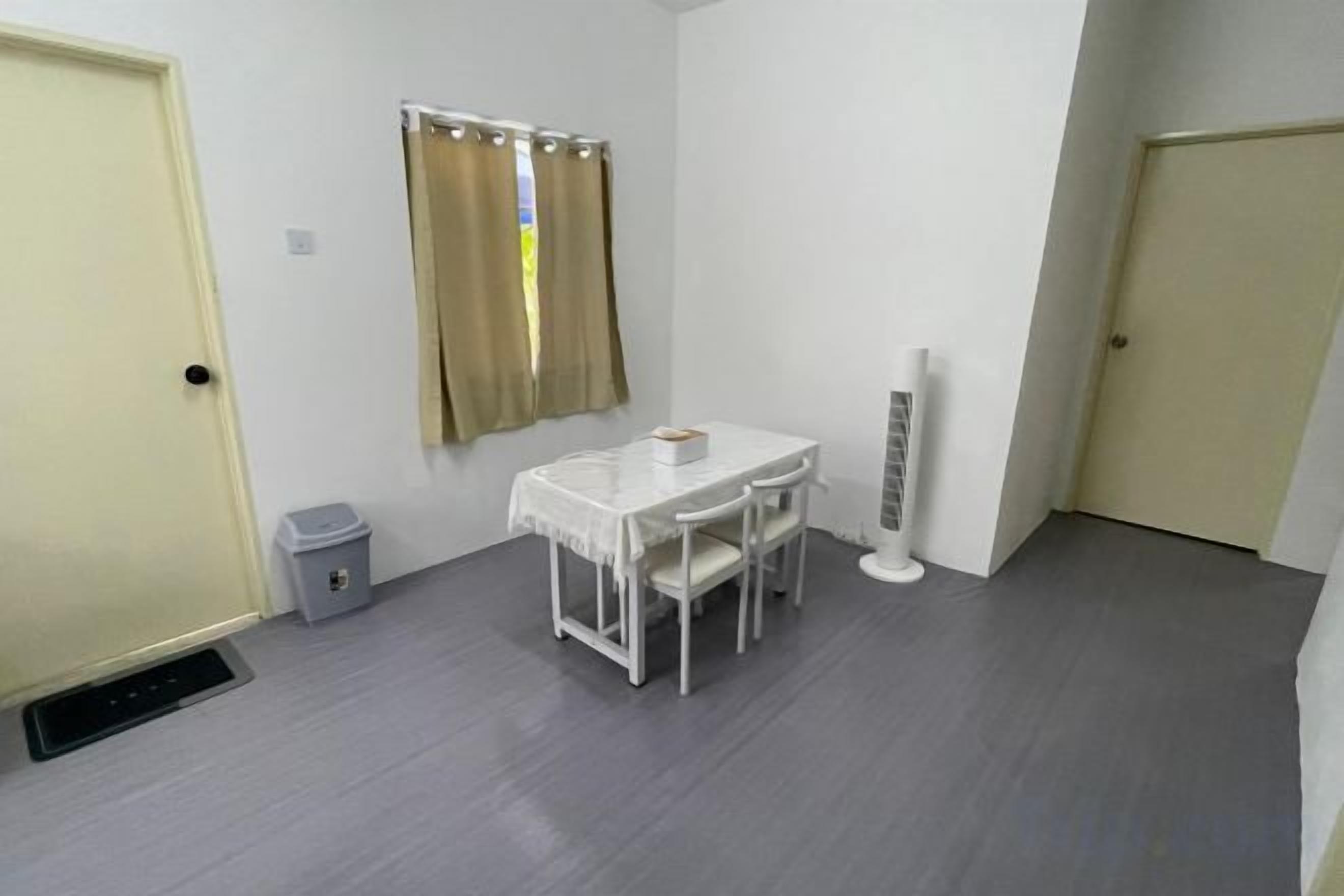 A small room with a white table and chairs, a window with curtains, and a radiator.