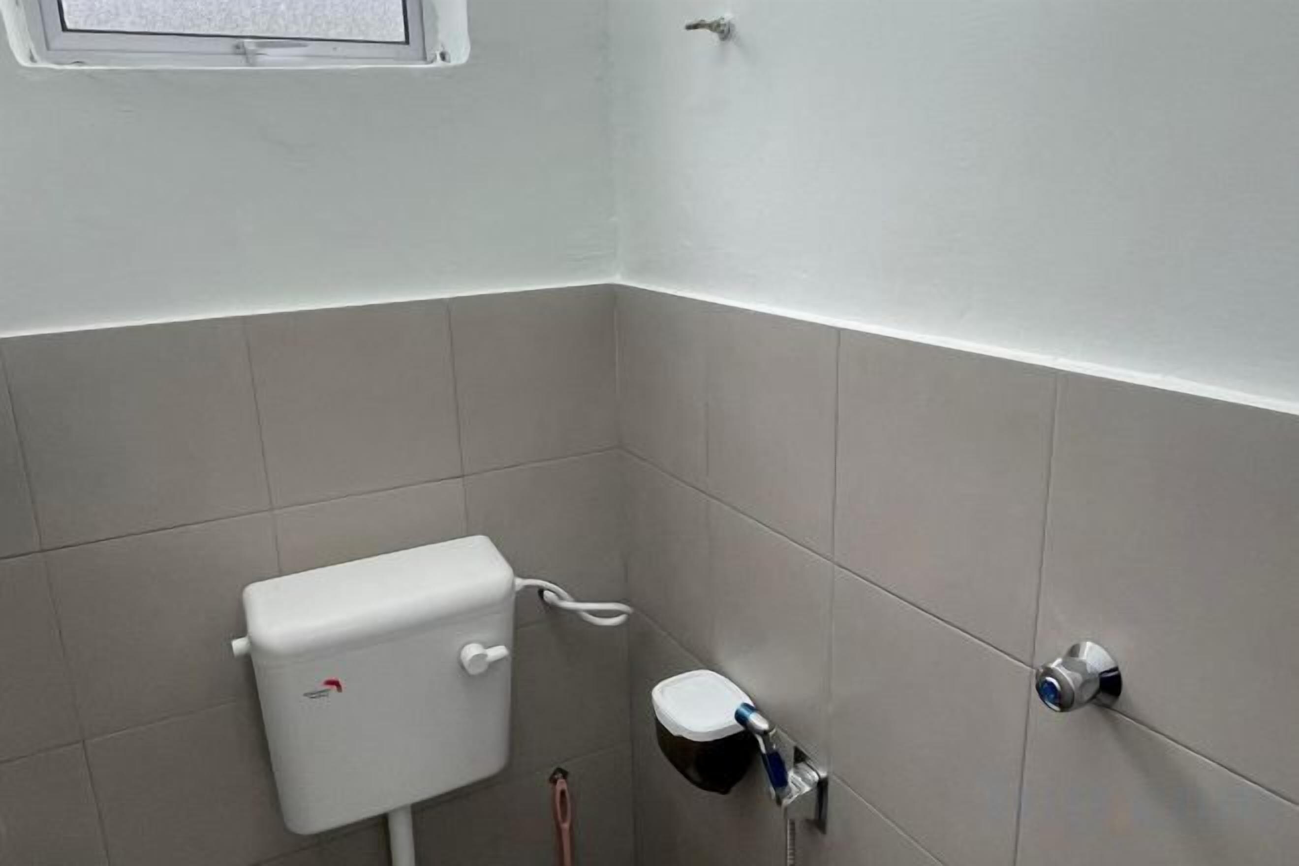 Um banheiro com vaso sanitário, bidê e torneira fixada na parede.