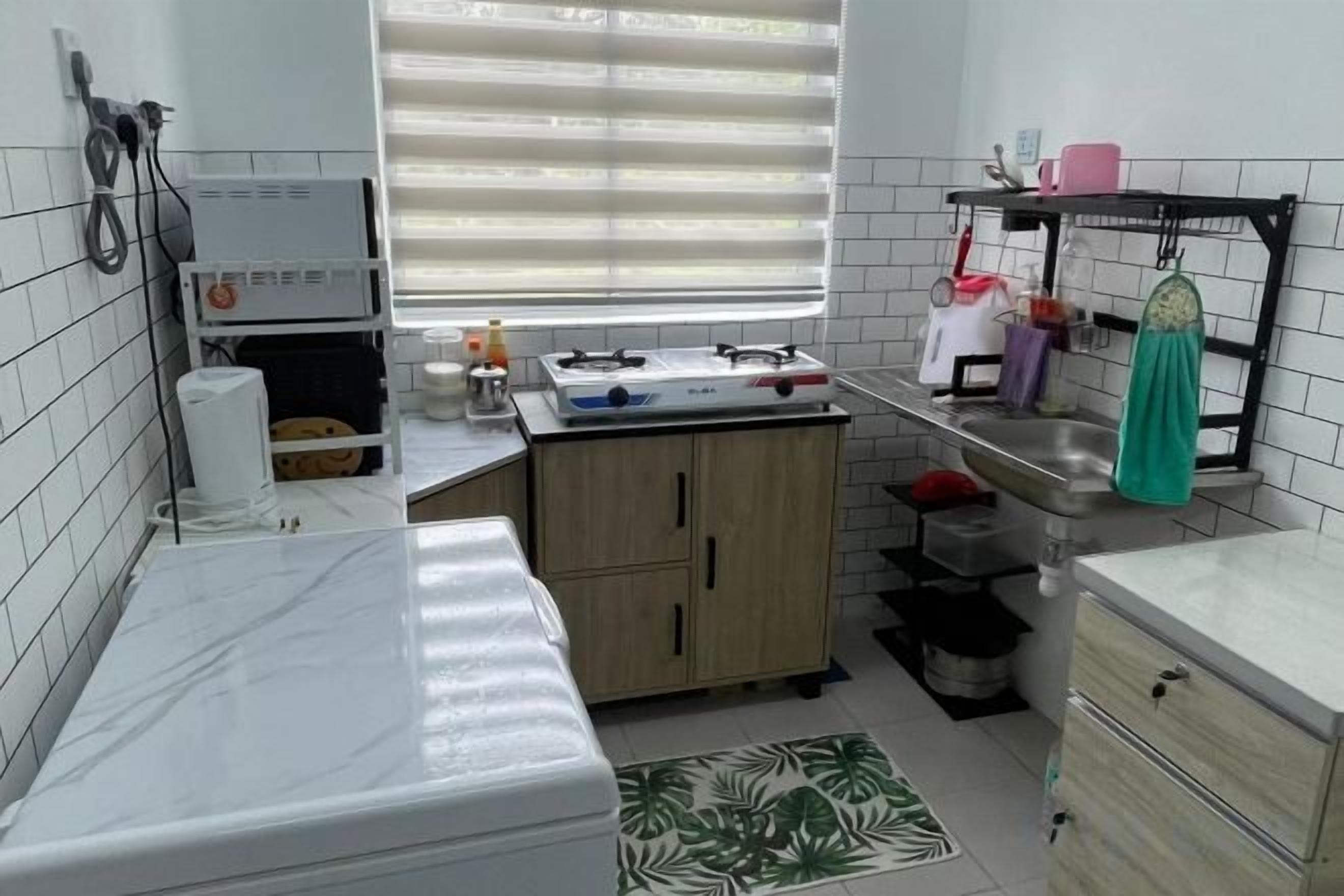 A compact kitchen with a sink, cabinets, and a window with blinds.