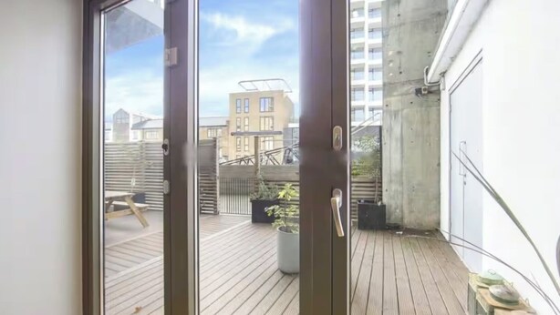 A balcony with a view of buildings and a wooden deck. - Spacious, Canal-Side, 3bed flat (London)