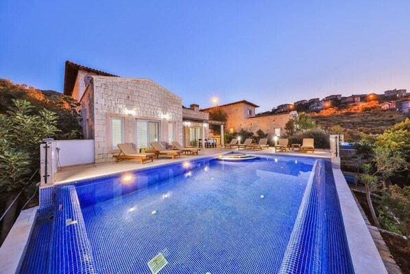A swimming pool with lounge chairs, a stone building, and a hillside view. - Villa Basil Amazing Sea view (Antalya)