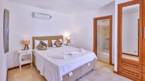 Ein Schlafzimmer mit Bett, Nachttischen, einem Kleiderschrank und einer Duschkabine.
