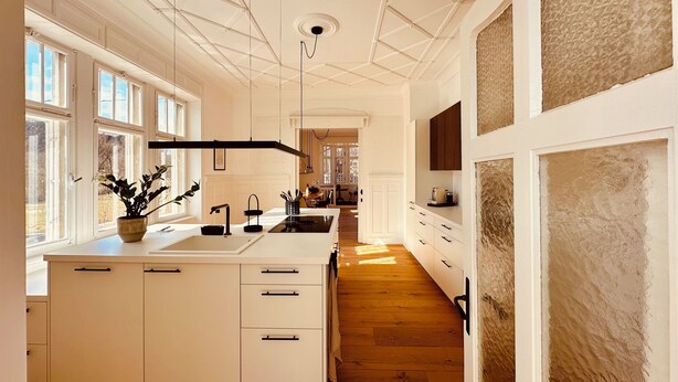 A spacious kitchen with a large island, white cabinetry, and a view into the dining area. - "Villa Suite" Spacious old villa with terrace near Stuttgart (Aidlingen)
