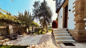 A paved patio with a stone bench and a table, surrounded by a wooden fence and trees. - "Villa Suite" Spacious old villa with terrace near Stuttgart (Aidlingen)
