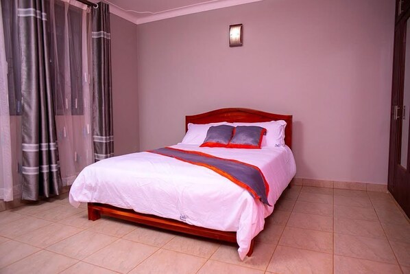 A bedroom with a bed, curtains, and a wall-mounted light fixture.