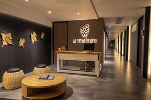 Un moderno vestíbulo de hotel con mostrador de recepción, taburetes de mimbre, una mesa redonda y decoración en la pared.