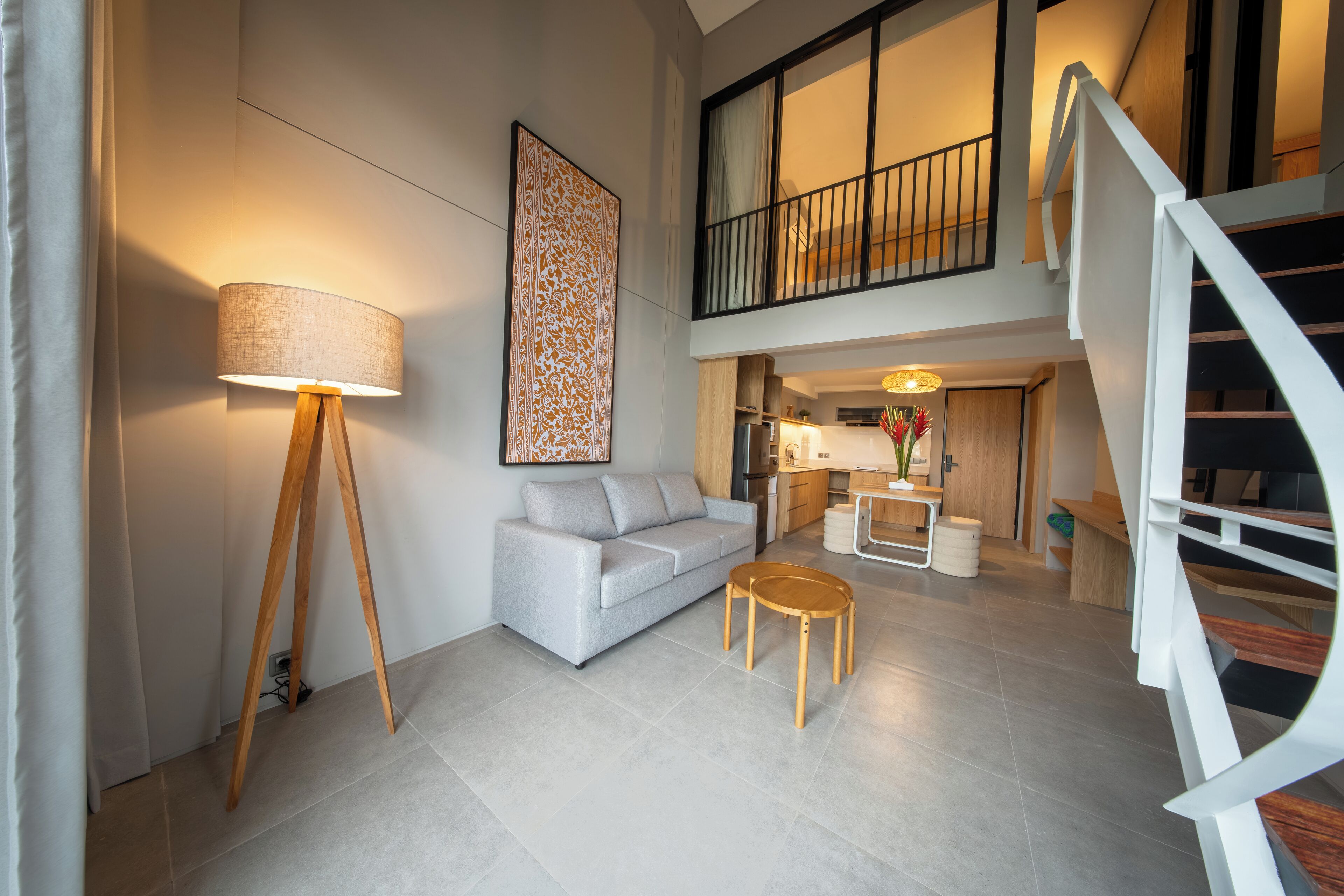 A modern living room with a sofa, a lamp, and a staircase.