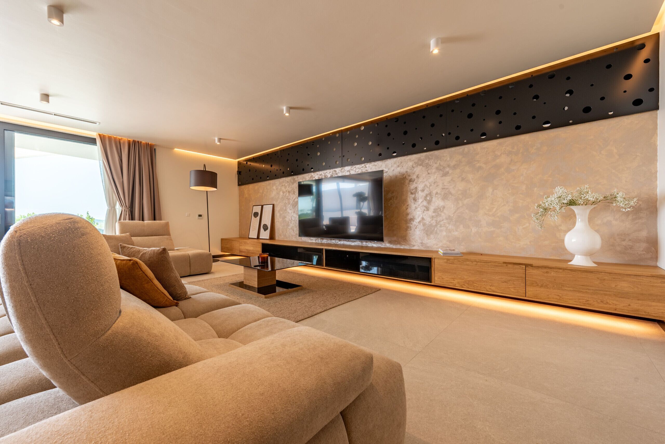 A modern living room with a large flat-screen TV, a sofa, and a coffee table.