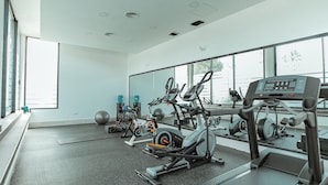 Uma academia moderna com diversos equipamentos de exercícios, janelas amplas e um layout espaçoso e limpo.