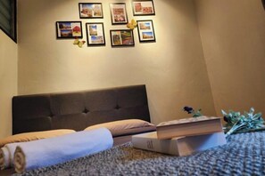 A bedroom with a bed, a wall-mounted picture, and a small table with a book. - Ipoh Rainbow Blissful Home (Ipoh)