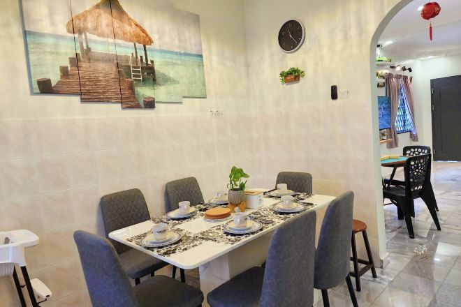 Un comedor con una larga mesa dispuesta para seis personas, rodeada de sillas, con un cuadro de un muelle en la pared.