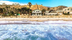 A beachfront property with a sandy beach, ocean waves, and a hillside with houses. - 25% Off Aug WkDays On The Sand, Perfect 4 Families (Ventura)