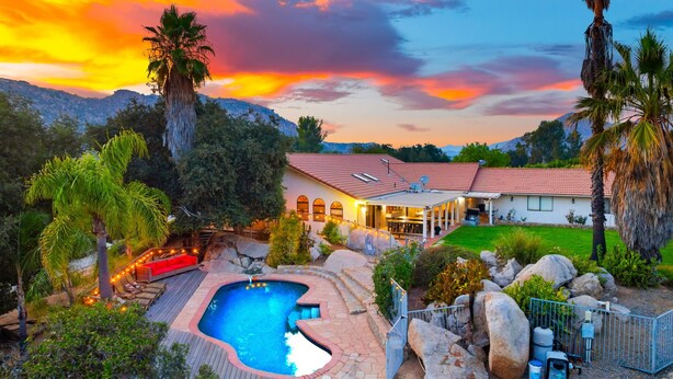 A house with a swimming pool, surrounded by large rocks and palm trees, with a mountainous backdrop. - Perfect For Families, Near Wineries W/Private Pool (Temecula)