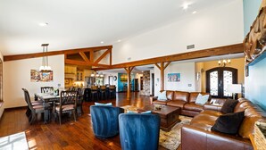 Un vaste espace de vie doté d’un plafond en bois, d’une table à manger avec des chaises et d’un canapé en cuir.
